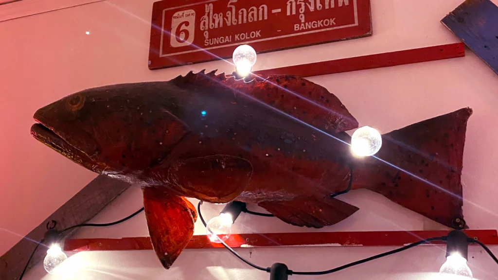 a wall decoration of a large red snapper fish with light bulbs on it