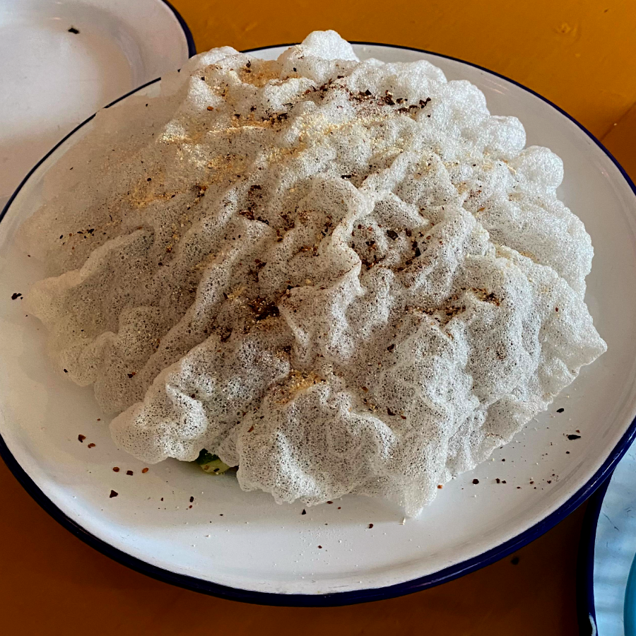 A large bumpy, textured white rice cracker covering the plate
