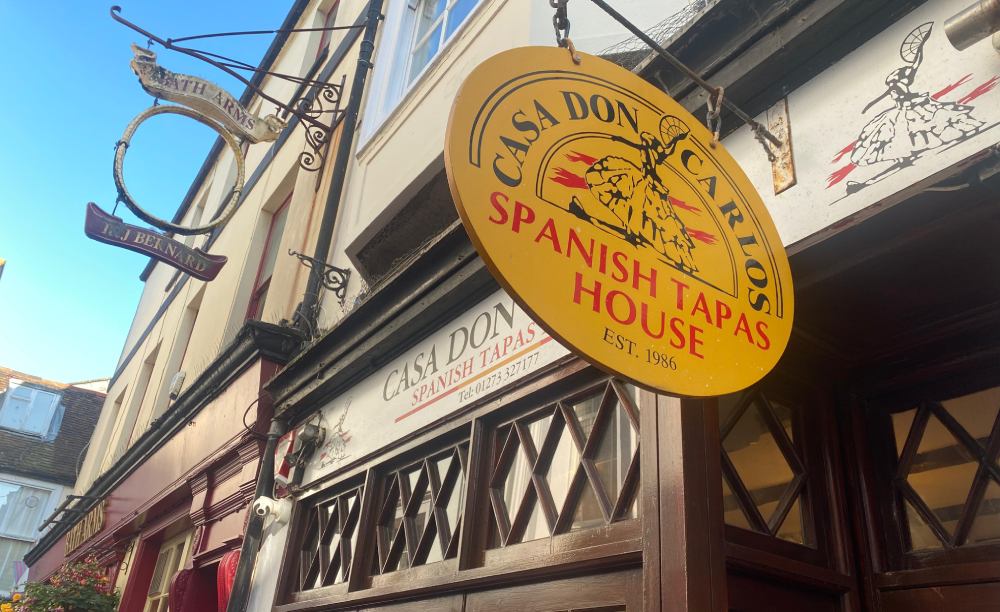 old fashioned yellow oval restaurant sign hanging outside building