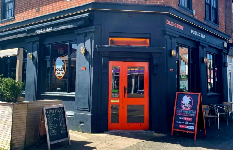 Exterior shot of 'old crow' pub, modern building with orange door and dark blue walls