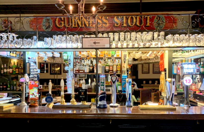 interior shot of traditional irish pub, with a Guiness stout logo above the bar