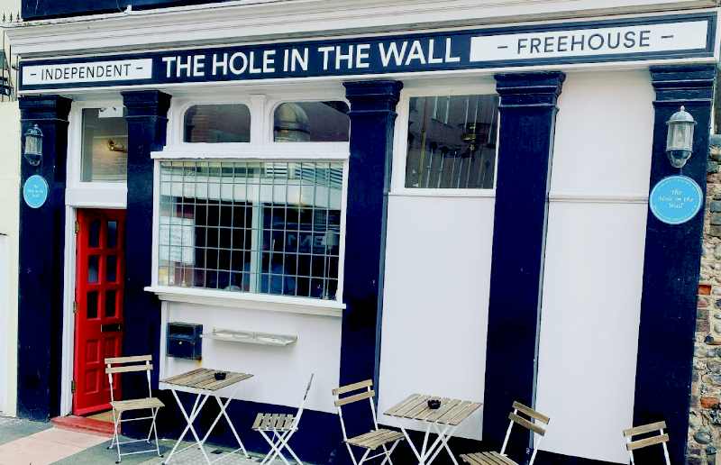 Exterior shot of old fashioned English pub, freehouse. With white and black paint and a red wooden door.
