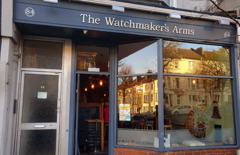 Exterior shot of The Watchmaker's Arms, a small pub. With a glass bay window, in a converted shop front.