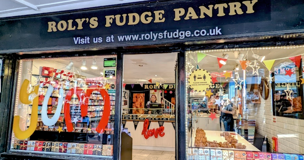Shop front of roly's fudge. Black exterior with colourful window display