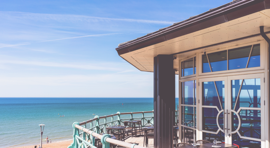 Exterior shot of traditional UK seaside restaurant, with blue sky and sea in the background