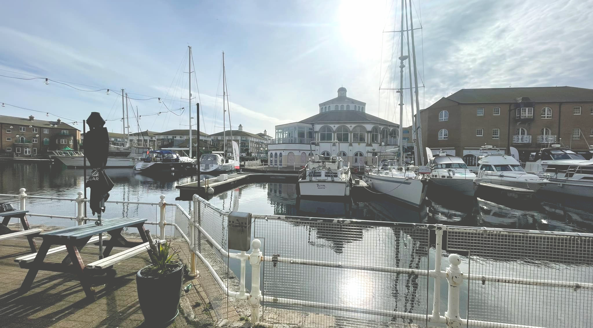 A wide shot of Brighton marina, several yachts are parked under a blue sky.